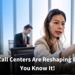 A female call center agent wearing a headset focuses on her computer screen as she assists a caller, while a colleague works in the background of a bright, modern office.