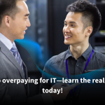 Two IT professionals discussing in a server room, with one holding a laptop and smiling. Text overlay reads: 'Stop overpaying for IT—learn the real cost today!